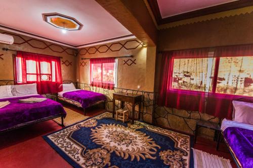 a room with two beds and a rug at Les Jardins De Todgha gorges de todra tinghir in Aït Baha