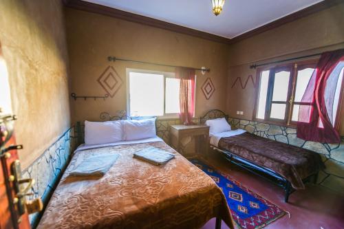 a bedroom with a bed and a couch and a window at Les Jardins De Todgha gorges de todra tinghir in Aït Baha