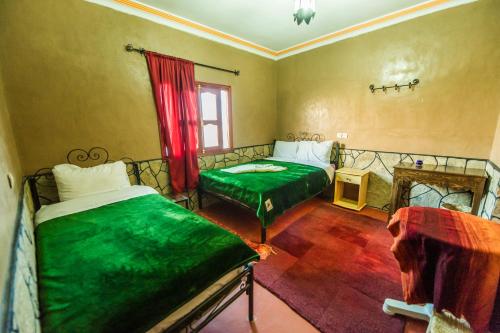 a bedroom with two beds with green sheets and a window at Les Jardins De Todgha gorges de todra tinghir in Aït Baha
