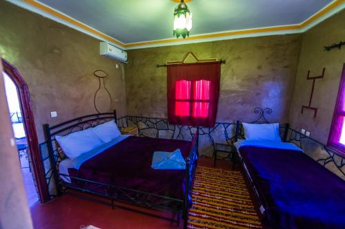 a bedroom with two beds and a red window at Les Jardins De Todgha gorges de todra tinghir in Aït Baha