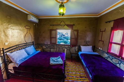 two beds in a room with purple sheets at Les Jardins De Todgha gorges de todra tinghir in Aït Baha