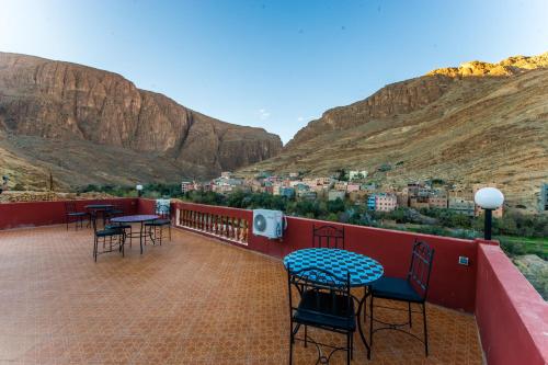 a balcony with tables and chairs and a view of a city at Les Jardins De Todgha gorges de todra tinghir in Aït Baha