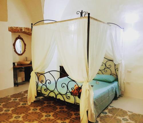 una camera con letto a baldacchino e tende bianche di La Casa dei Bombi Nettare & Polline a Matino
