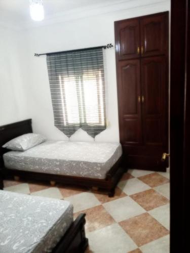 two beds in a room with a window and a floor at Martil Beach Down Town in Martil