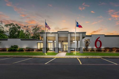 a building with two flags in a parking lot at Motel 6-Henderson, TX in Henderson