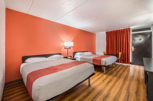 two beds in a room with orange walls at Motel 6-Henderson, TX in Henderson