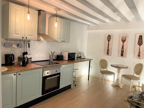 a kitchen with white cabinets and a table and chairs at No 14 Cádiz in Cádiz