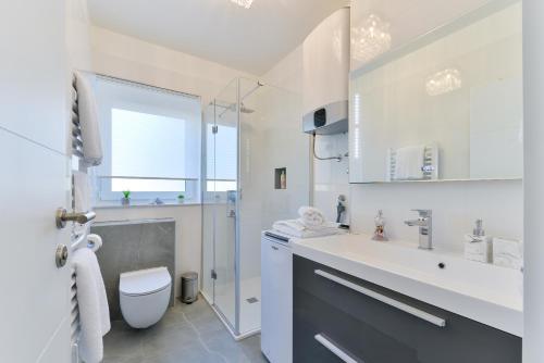 ein weißes Bad mit einem Waschbecken und einem WC in der Unterkunft PIA Apartment in Zadar