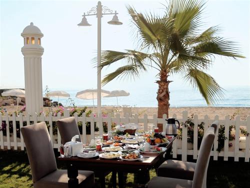 un tavolo con cibo e una palma sulla spiaggia di Sahil Martı Hotel a Mezitli