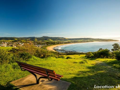 a bench sitting on a hill overlooking a beach at Blue View Gerringong in Gerringong