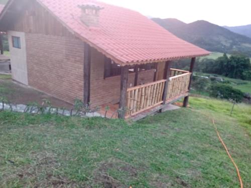 una pequeña casa con techo rojo en un campo en Pousada Rancho da Montanha en Visconde De Maua