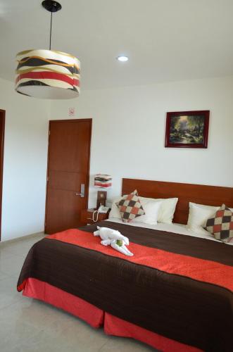 a bedroom with a bed with a stuffed animal on it at Hotel Real Mercedes in Mérida
