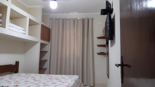 a bedroom with a bed and a shower curtain at Edifício San Rafael in Ubatuba