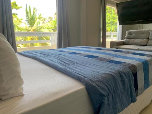 a bed with a blue and white blanket and a window at Temporada Litorânea slz in São Luís