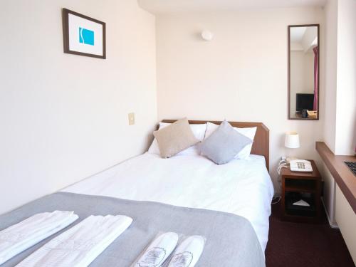 1 dormitorio con 1 cama con sábanas blancas y espejo en Pod Select Hotel Shinjuku, en Tokio