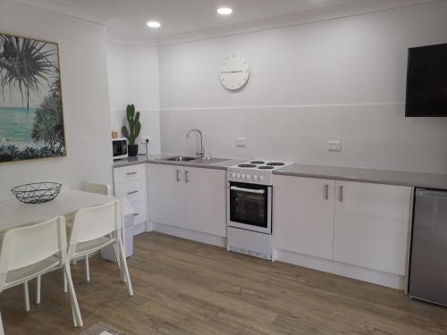 a kitchen with white cabinets and a table and a clock at Bay of Palms in Gold Coast