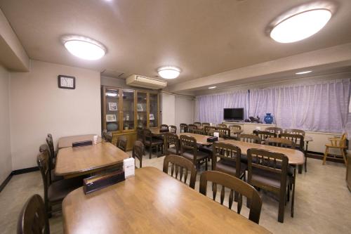 a dining room with tables and chairs and a television at Heiwadai Hotel Arato in Fukuoka