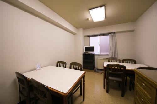 a room with two tables and chairs and a television at Heiwadai Hotel Arato in Fukuoka
