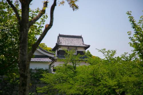 an asian style building with trees in the foreground at Heiwadai Hotel Arato in Fukuoka