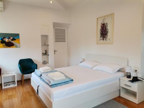 a white bedroom with a white bed and a chair at Vera in Split