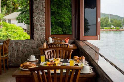 a table with plates of food on a porch at Colibri Hotel in Baie Sainte Anne