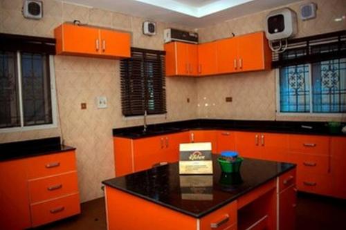 a kitchen with orange cabinets and a black counter top at Mexiloyd Hotel - Deluxe Studio in Port Harcourt