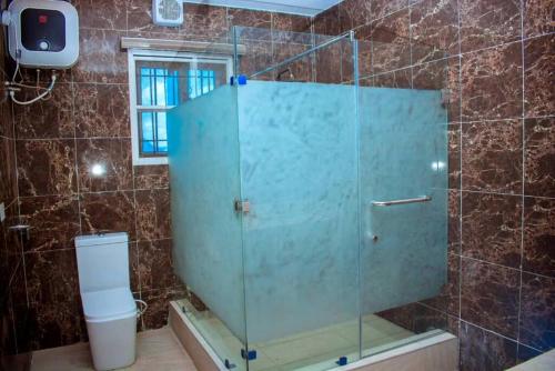 a glass shower in a bathroom with a toilet at Mexiloyd Hotel - Deluxe Studio in Port Harcourt