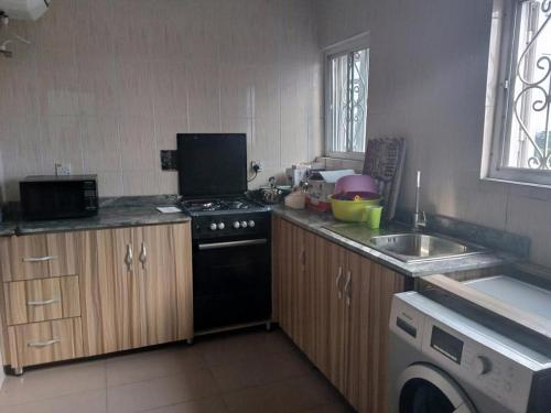 a small kitchen with a stove and a sink at Room in Lodge - Blooms Spot Hotel and Suites in Port Harcourt