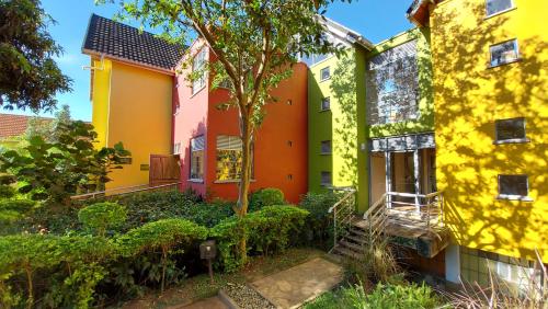 una casa amarilla y naranja con un árbol en el patio en Yellow Haven Lodge en Kampala