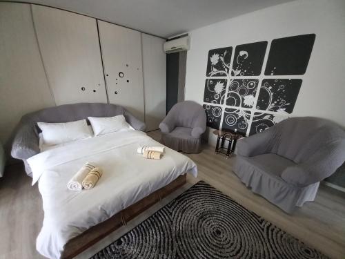 ein Schlafzimmer mit einem Bett und zwei Stühlen darin in der Unterkunft Casa Crinei in Jurilovca