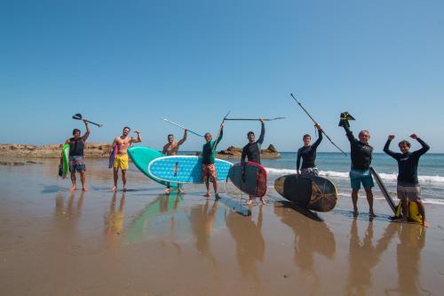 a group of people standing on the beach with their surfboards at El Refugio de Vichayito in Vichayito