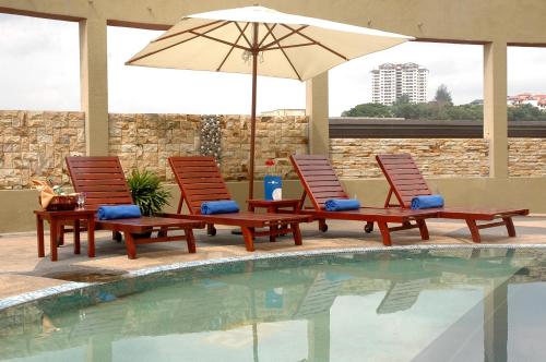 two chairs and an umbrella next to a pool at Oriental Crystal Hotel in Kajang