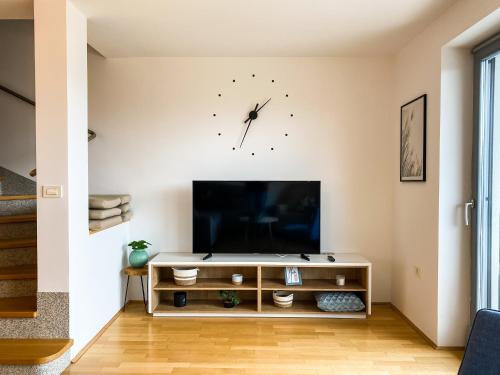a living room with a tv and a clock on the wall at Lakeview Villa Bled in Bled