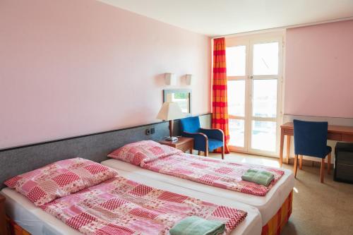 1 dormitorio con 2 camas, escritorio y ventana en Hotel Négy Évszak, en Siófok