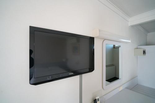a flat screen tv hanging on a wall next to a mirror at Olympia Motel in Queanbeyan