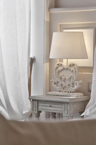 a lamp on a table in a room with a mirror at Les Glycines - Hôtel & Spa - Teritoria in Les Eyzies-de-Tayac
