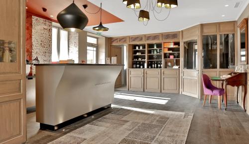 a kitchen with a bar and a dining area at Les Glycines - Hôtel & Spa - Teritoria in Les Eyzies-de-Tayac