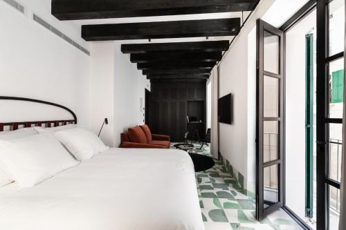 a bedroom with a white bed and a chair at Concepcio by Nobis, Palma, a Member of Design Hotels in Palma de Mallorca
