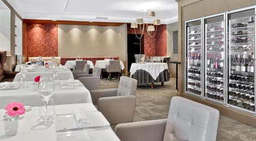 a restaurant with white tables and chairs and wine racks at Les Glycines - Hôtel & Spa - Teritoria in Les Eyzies-de-Tayac