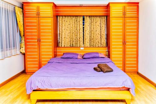 a bedroom with a bed with yellow doors and purple sheets at JOLLY GUESTHOUSE & RESTAURANT in Pattaya