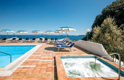 una piscina con sedie a sdraio e ombrelloni di Hotel Bagnitiello a Ischia