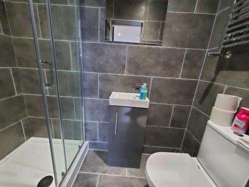 a bathroom with a shower and a toilet and a sink at The Ashcroft Apartments Free Parking in Manchester