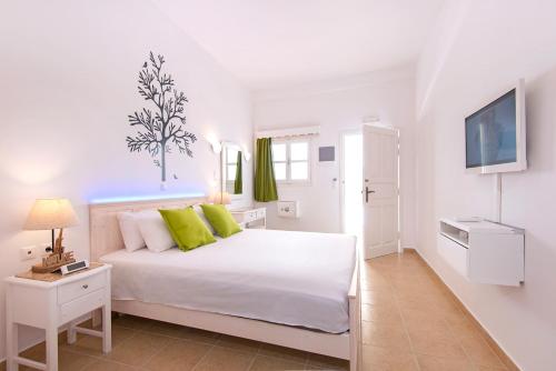 a white bedroom with a white bed and a tv at Lindos Harmony Suites in Lindos