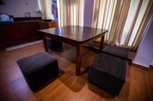 a wooden table and two stools in a room at Waves Beach House in Puducherry