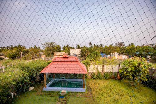 a gazebo with a red roof in a yard at Waves Beach House in Puducherry