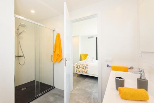 a white bathroom with a shower and a bedroom at Villa Dolce Vita in Son Bou
