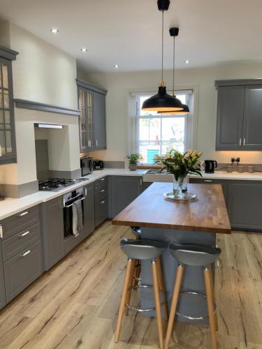 uma cozinha com armários cinzentos e uma mesa de madeira com bancos em No. 16 Lytham em Lytham St Annes