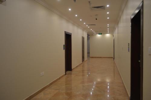 a hallway with white walls and a long hallway with doors at فندق كارم in Raḩīmah