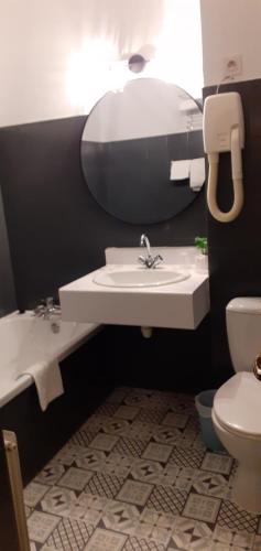 a bathroom with a sink and a toilet and a mirror at Hôtel Athéna in Agde