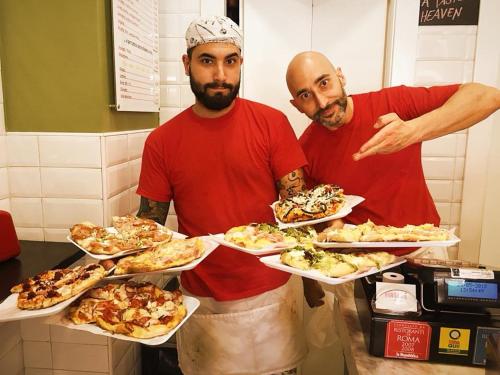 two men standing in a kitchen with plates of food at Roma Veneto Relais in Rome